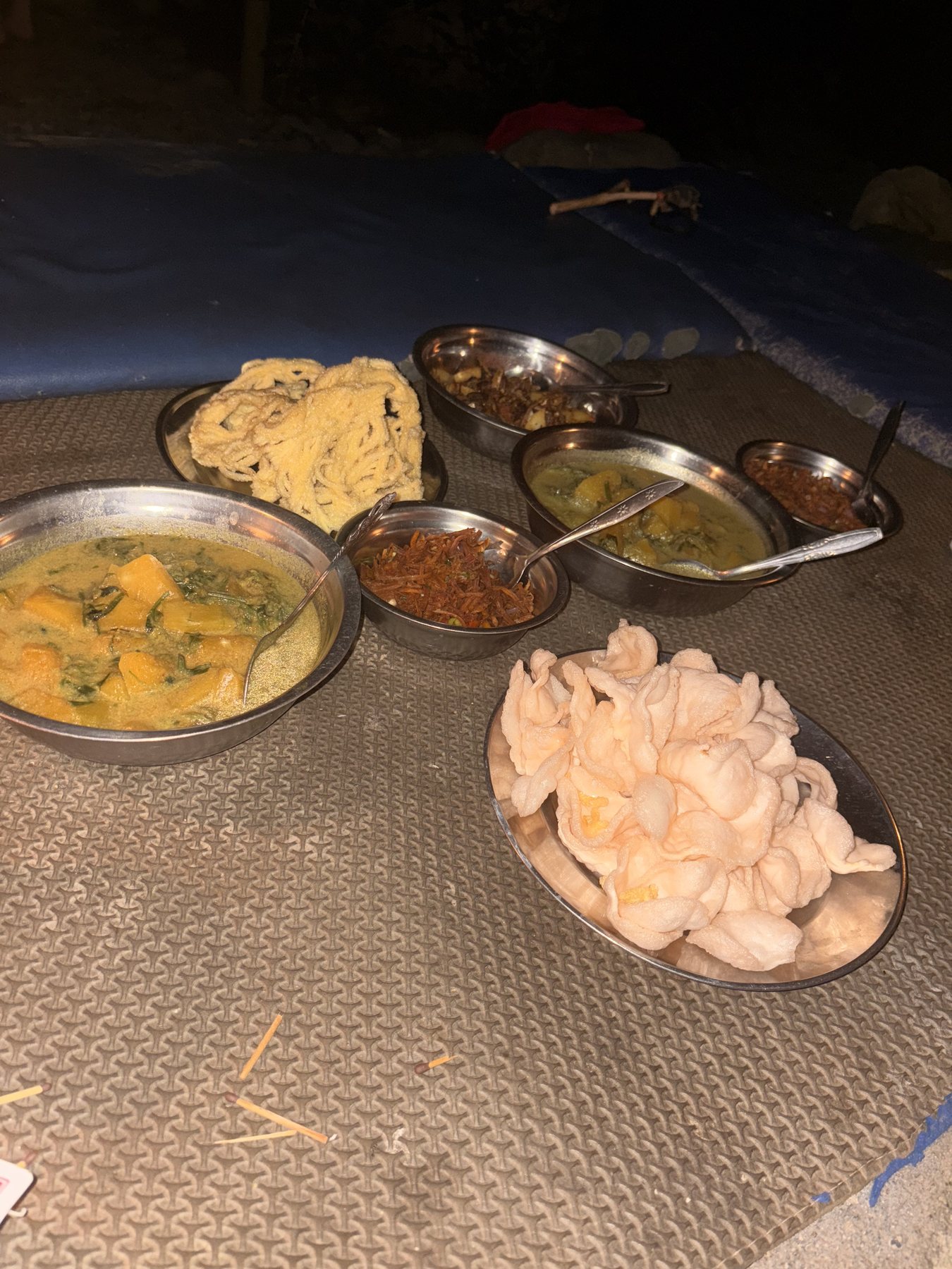A shared Southeast Asian meal with curries, rice crackers and side dishes